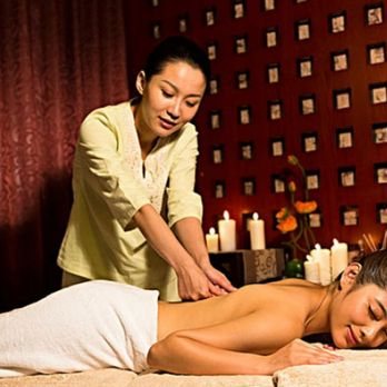 A therapist giving a guest a calm back massage in a candle-lit room